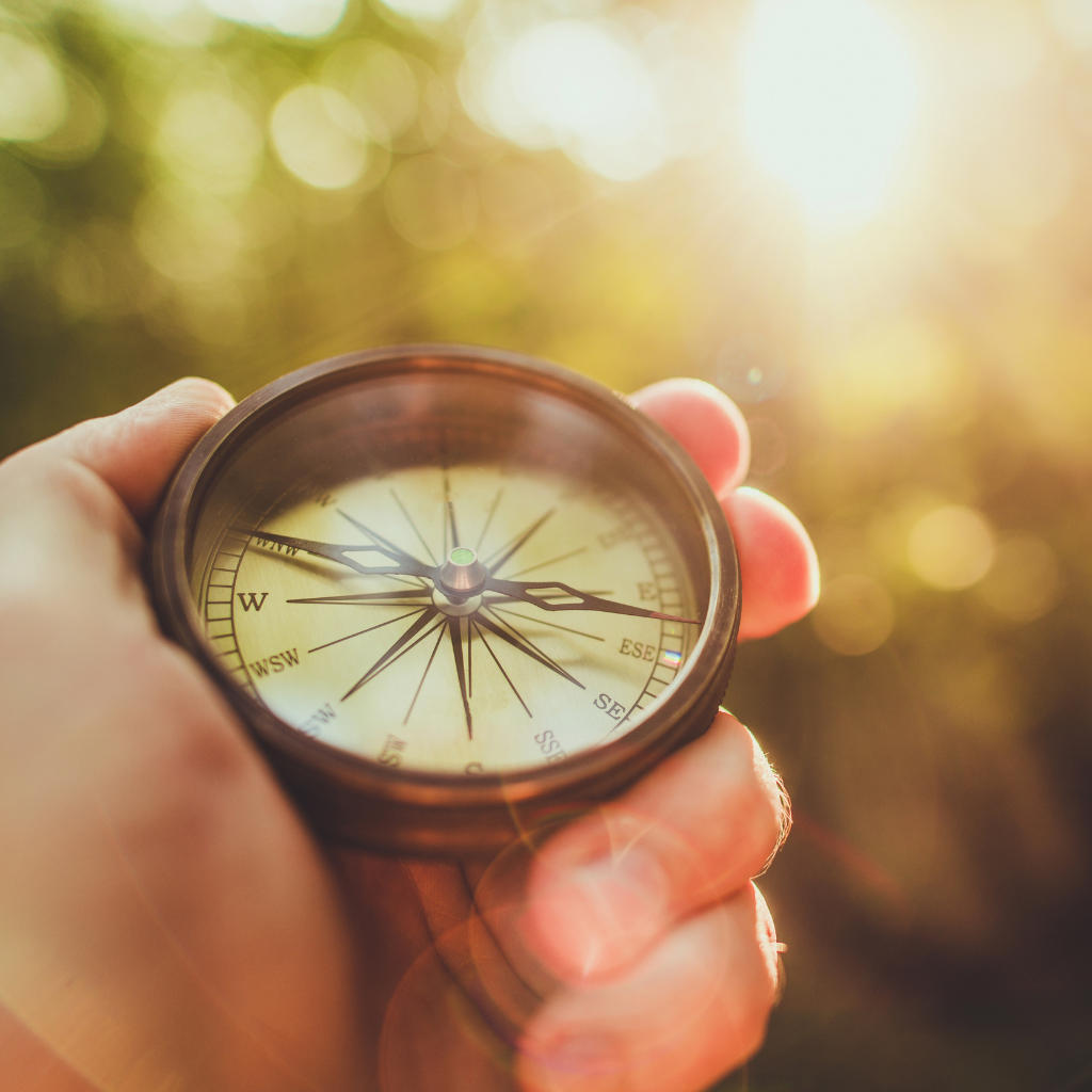 A closeup of a hand holding a compass. Signifying ikigai-kan is a force that points your compass towards your purpose in life.